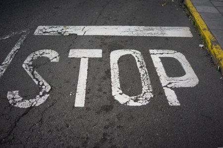 Stop Zeichen auf dem Asphalt neben gelbem Bordsteinrand